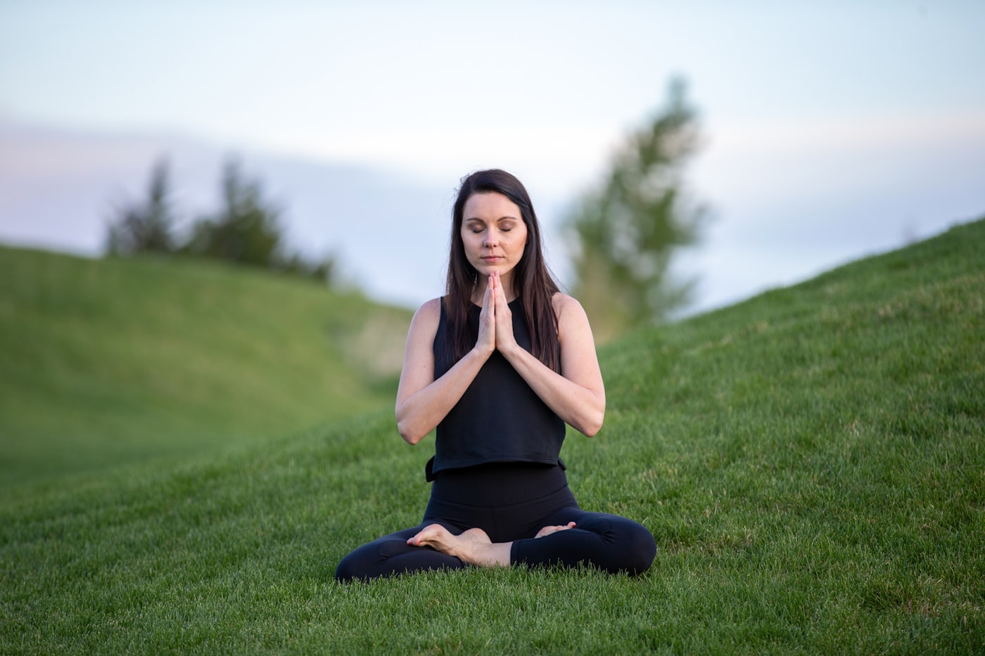 Persona en meditación, en calma, sobre un entorno verde natural